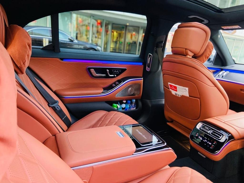 Rear cabin of a chauffeur-driven Mercedes-Benz S-Class with fastened seatbelts, bottled water and reading material ready for a passenger