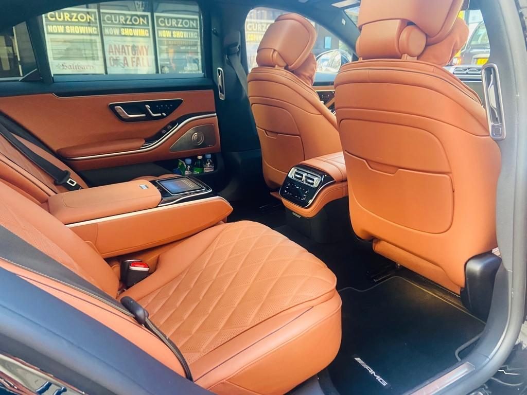 Rear cabin of a chauffeur-driven Mercedes-Benz S-Class with tan leather seats, parked on a London street