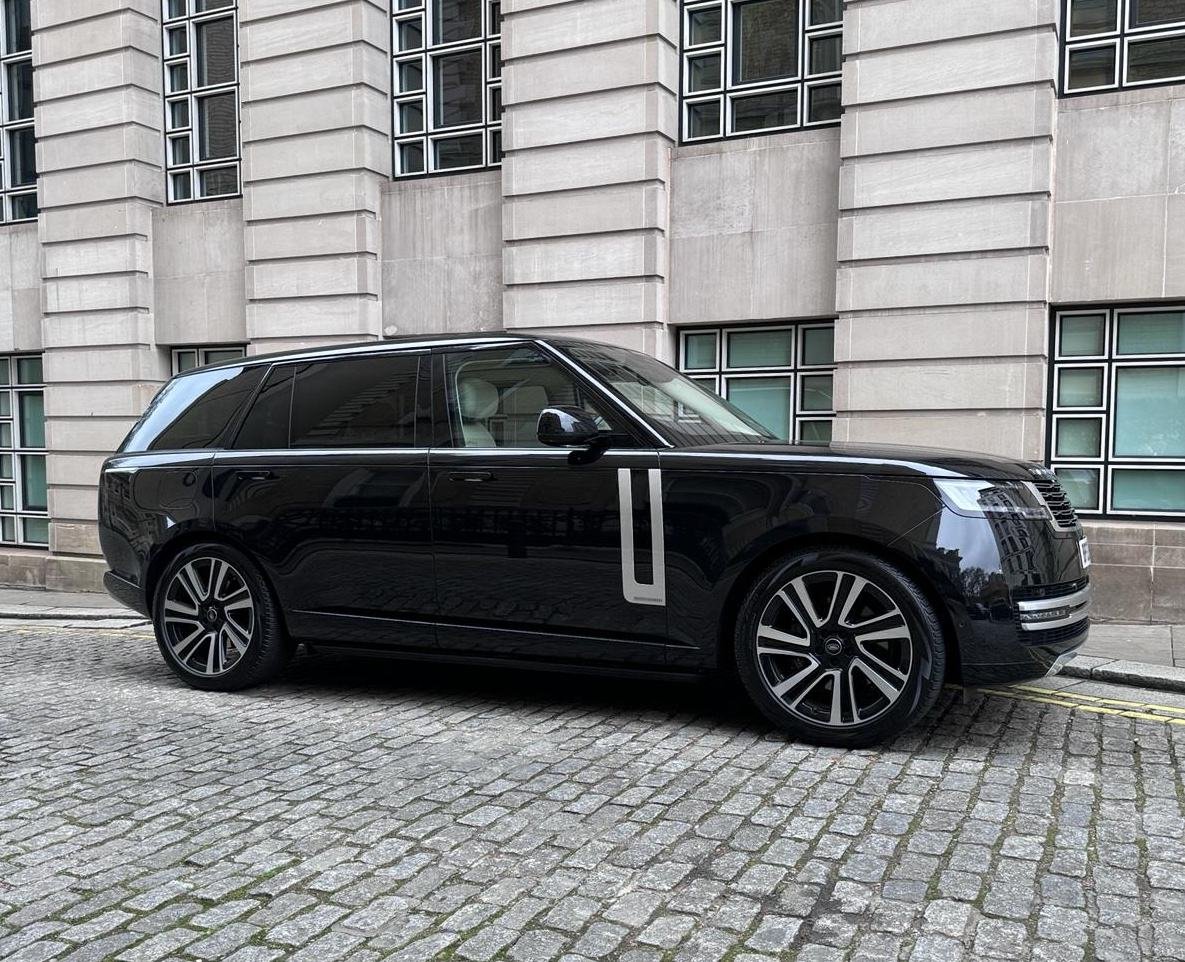 Black Range Rover chauffeur car parked on a cobbled street beside a stone office building in the City of London