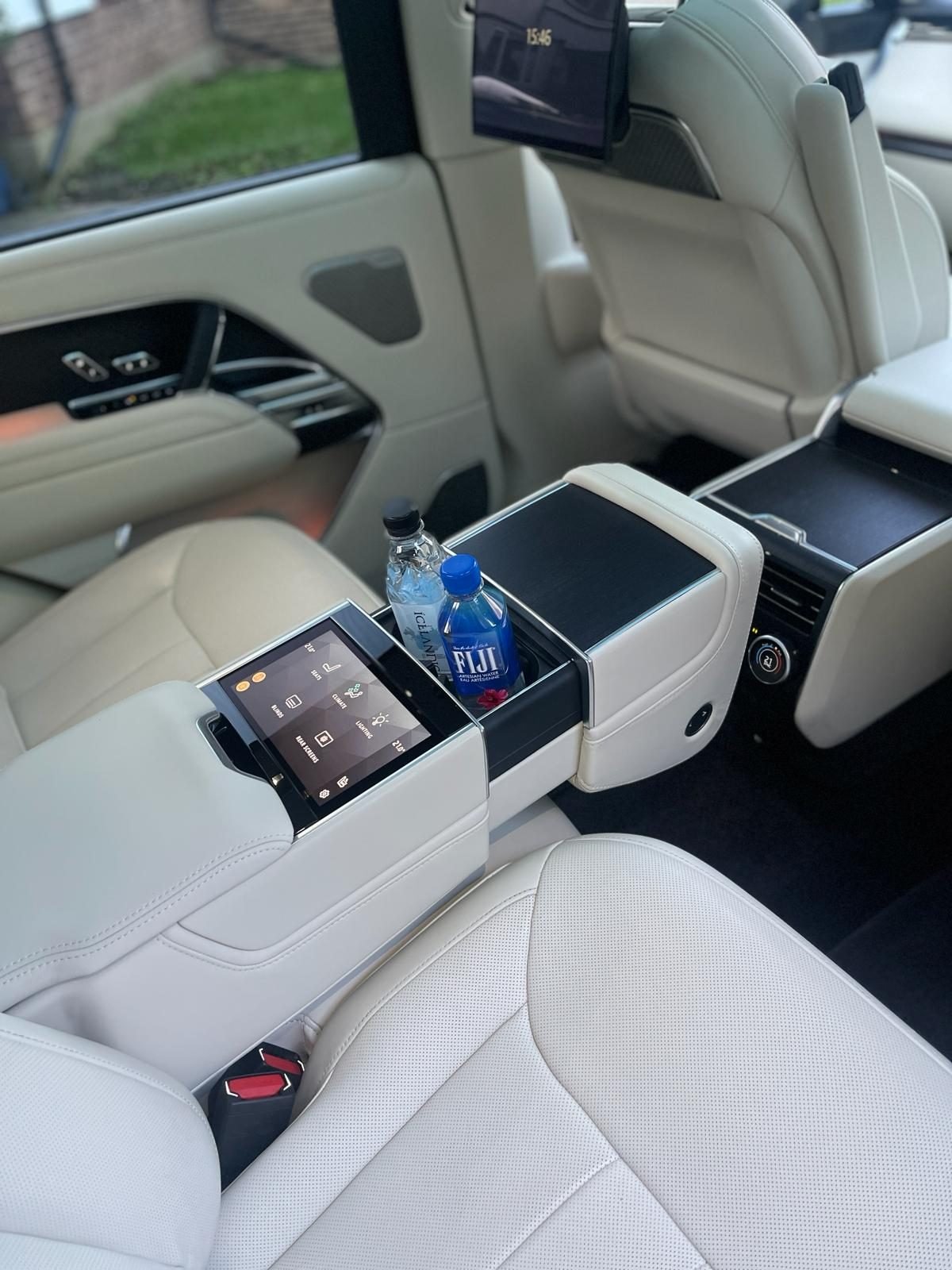 Rear cabin of a Range Rover chauffeur car with cream leather seats and bottled water